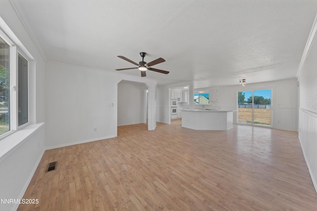 1314 Johnson Ln, Minden, NV 89423 - unfurnished living room featuring a ceiling fan, light wood-style flooring, a textured ceiling, and arched walkways