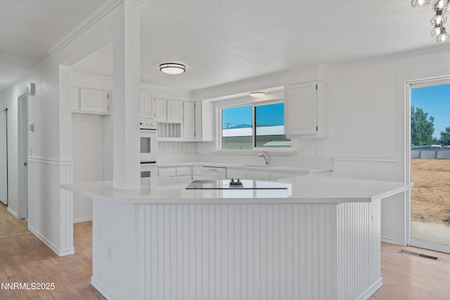 1314 Johnson Ln, Minden, NV 89423 - kitchen featuring light wood-style floors, light countertops, white cabinets, white double oven, and a textured ceiling