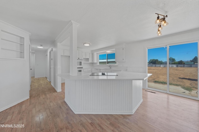 1314 Johnson Ln, Minden, NV 89423 - kitchen with light countertops, black electric cooktop, white cabinetry, light wood-style floors, and double oven
