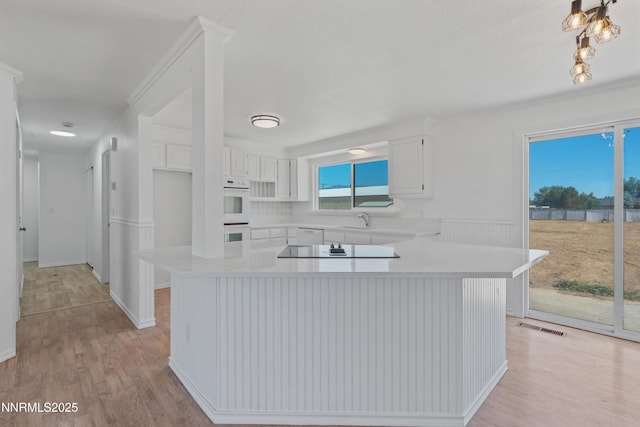 1314 Johnson Ln, Minden, NV 89423 - kitchen with light countertops, light wood-style flooring, white cabinets, double oven, and a center island