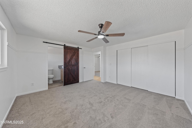 1314 Johnson Ln, Minden, NV 89423 - unfurnished bedroom featuring a barn door, a closet, carpet, a textured ceiling, and ensuite bathroom