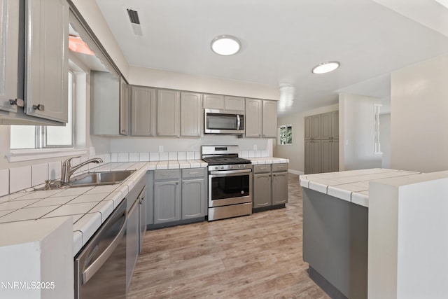 1513 S Riverview Dr, Gardnerville, NV 89460 - kitchen featuring appliances with stainless steel finishes, gray cabinetry, tile counters, and light wood-style flooring