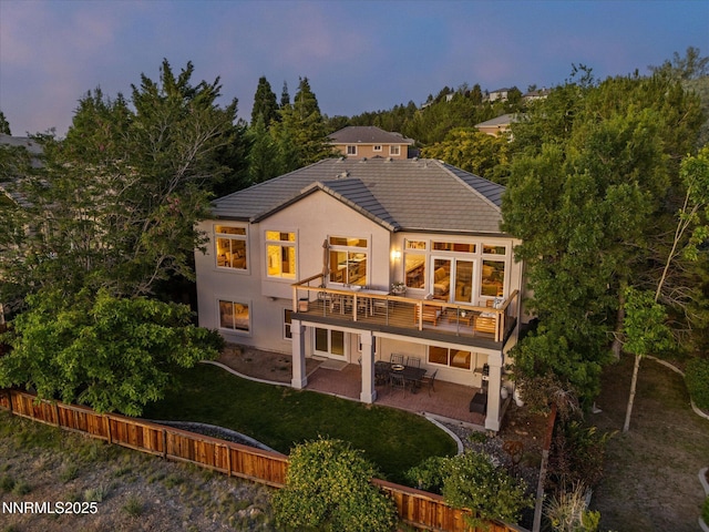 4721 W Creek Ridge Trl, Reno, NV 89519 - back of house at dusk with a patio area, a tiled roof, stucco siding, a yard, and a deck