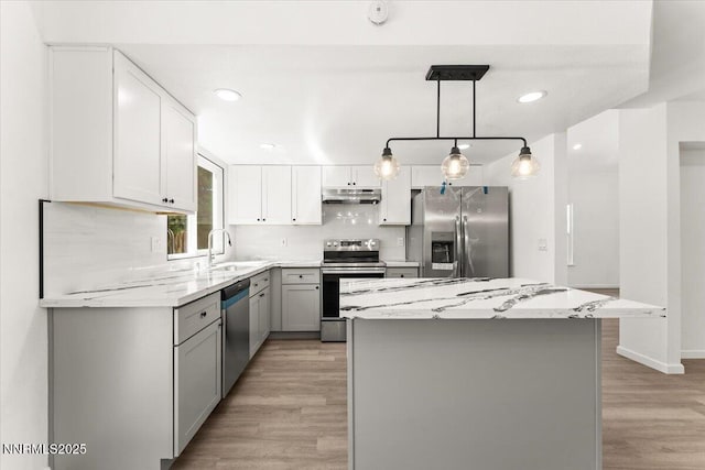 2719 Chavez Dr, Reno, NV 89502 - kitchen with appliances with stainless steel finishes, under cabinet range hood, gray cabinets, decorative backsplash, and a center island