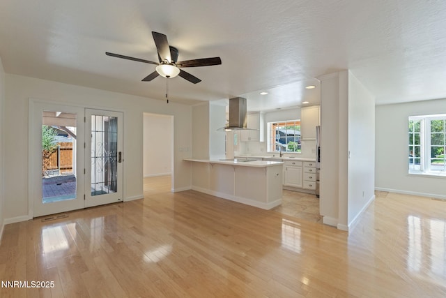 2095 Kings Row, Reno, NV 89503 - kitchen with wall chimney range hood, light wood finished floors, a peninsula, light countertops, and a breakfast bar area
