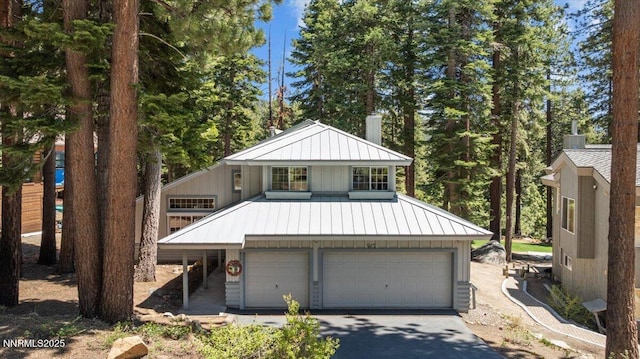 917 Jennifer St, Incline Village, NV 89451 - view of front of house with a standing seam roof, a garage, a metal roof, a chimney, and asphalt driveway