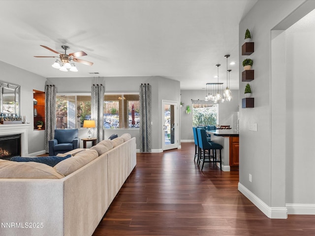 1486 Lambrays Ct, Sparks, NV 89436 - living room featuring dark wood-style flooring, a glass covered fireplace, a ceiling fan, and plenty of natural light