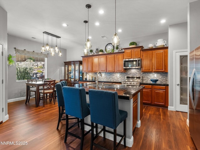 1486 Lambrays Ct, Sparks, NV 89436 - kitchen featuring appliances with stainless steel finishes, brown cabinets, dark countertops, tasteful backsplash, and dark wood-type flooring