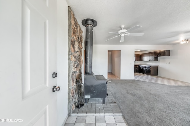 8720 Aquifer Way, Reno, NV 89506 - living area with a wood stove, a ceiling fan, a textured ceiling, and light colored carpet