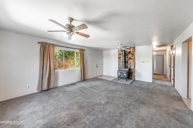 8720 Aquifer Way, Reno, NV 89506 - unfurnished living room featuring a wood stove, a ceiling fan, carpet, and a textured ceiling