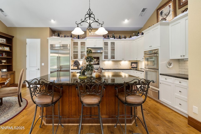 16956 Rue Du Parc Ave, Reno, NV 89511 - kitchen with appliances with stainless steel finishes, decorative backsplash, white cabinets, glass insert cabinets, and recessed lighting
