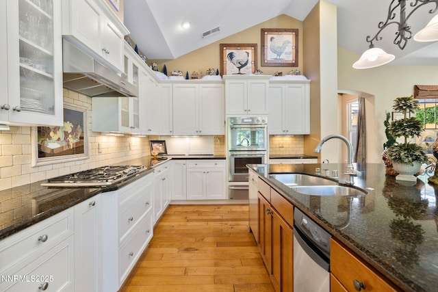 16956 Rue Du Parc Ave, Reno, NV 89511 - kitchen featuring appliances with stainless steel finishes, arched walkways, vaulted ceiling, light wood finished floors, and white cabinetry