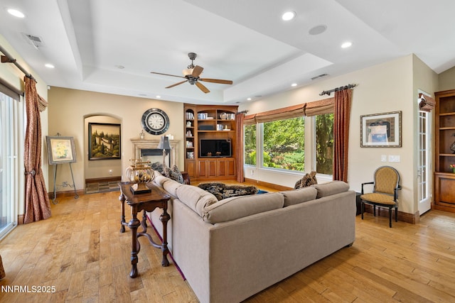 16956 Rue Du Parc Ave, Reno, NV 89511 - living room featuring a tray ceiling, light wood-type flooring, a ceiling fan, recessed lighting, and a fireplace