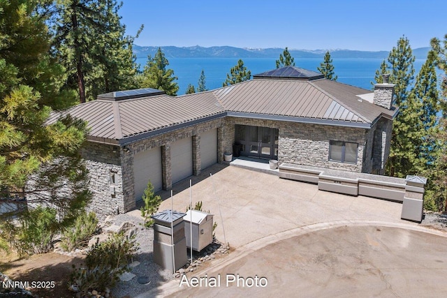 275 Chukkar Dr, Glenbrook, NV 89413 - view of front facade featuring stone siding, a garage, concrete driveway, french doors, and a metal roof