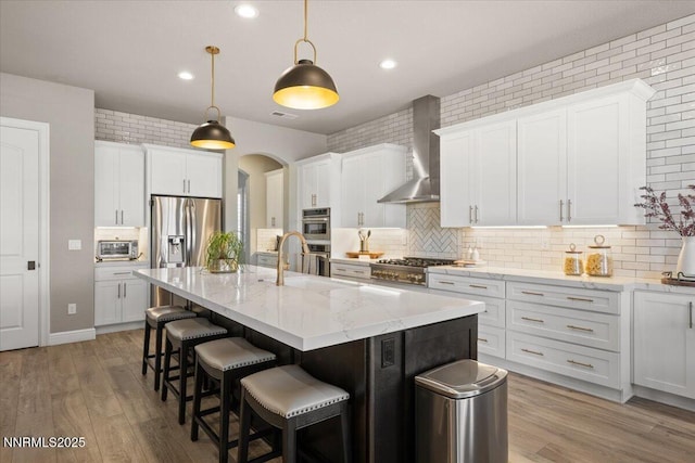 10 Diamond Strm Ct, Sparks, NV 89441 - kitchen featuring wall chimney exhaust hood, decorative backsplash, appliances with stainless steel finishes, a center island with sink, and a breakfast bar