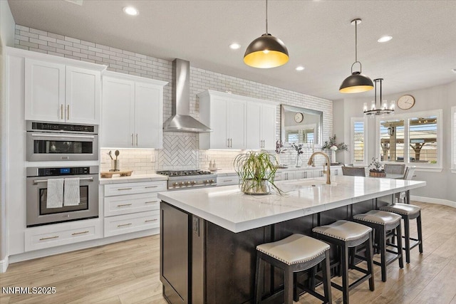 10 Diamond Strm Ct, Sparks, NV 89441 - kitchen with wall chimney range hood, a kitchen island with sink, light wood-style flooring, white cabinetry, and stainless steel appliances