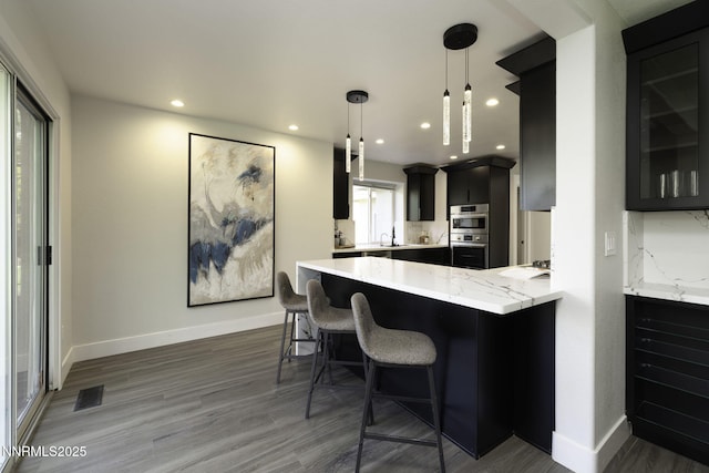 3323 Deer Ridge Ct, Reno, NV 89509 - kitchen with double oven, wood finished floors, a kitchen breakfast bar, a peninsula, and dark cabinetry