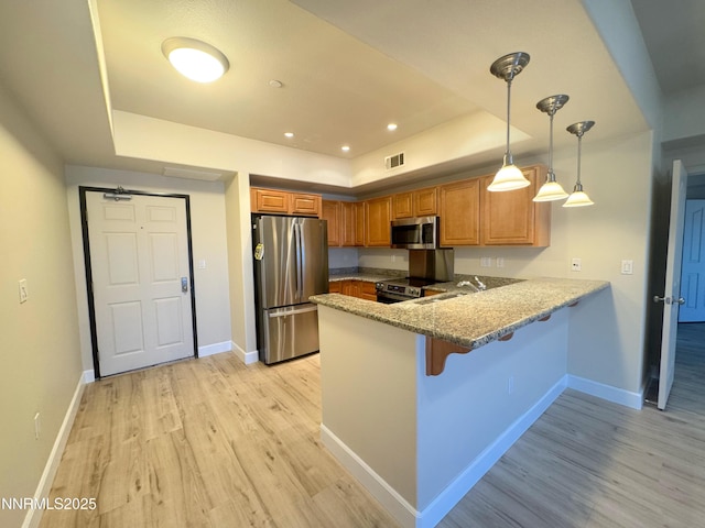 200 W 2nd St Unit 1107, Reno, NV 89501 - kitchen featuring stainless steel appliances, a tray ceiling, a peninsula, light wood-style floors, and brown cabinetry