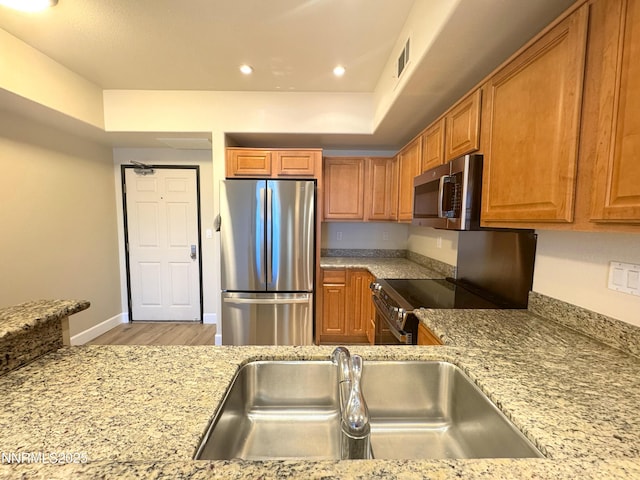 200 W 2nd St Unit 1107, Reno, NV 89501 - kitchen with appliances with stainless steel finishes, wood finished floors, brown cabinets, light stone countertops, and recessed lighting