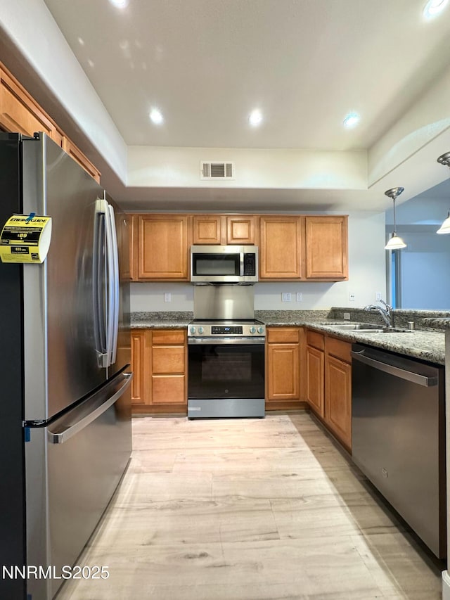 200 W 2nd St Unit 1107, Reno, NV 89501 - kitchen with appliances with stainless steel finishes, light wood-type flooring, a raised ceiling, brown cabinetry, and recessed lighting