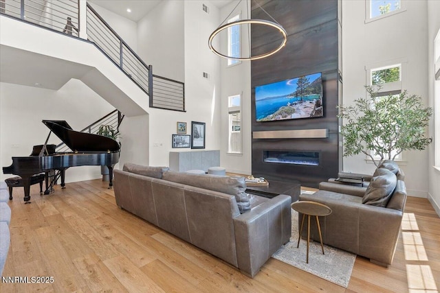 206 Criollo Ct, Reno, NV 89511 - living room with a towering ceiling, light wood-style flooring, stairway, and a glass covered fireplace