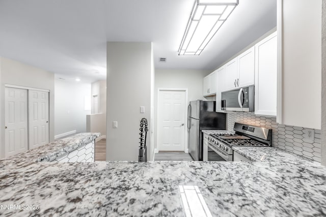 900 S Meadows Pkwy Apt 322, Reno, NV 89521 - kitchen with stainless steel appliances, light stone countertops, backsplash, white cabinets, and light wood finished floors