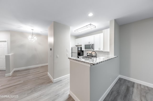 900 S Meadows Pkwy Apt 322, Reno, NV 89521 - kitchen with stainless steel microwave, freestanding refrigerator, white cabinets, decorative backsplash, and light wood-style flooring