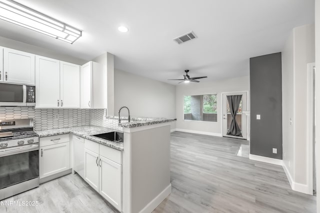 900 S Meadows Pkwy Apt 322, Reno, NV 89521 - kitchen with gas stove, a peninsula, white cabinetry, tasteful backsplash, and recessed lighting
