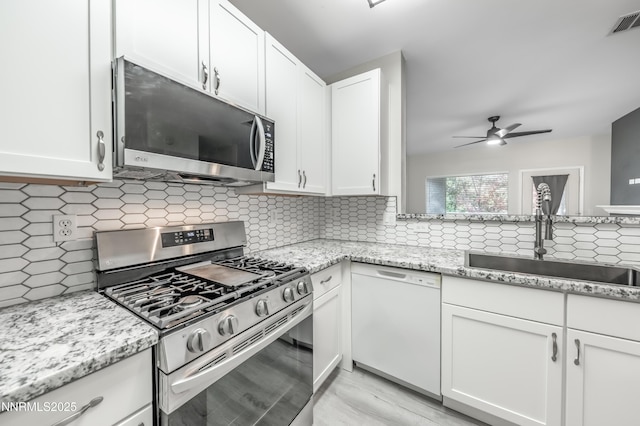 900 S Meadows Pkwy Apt 322, Reno, NV 89521 - kitchen featuring appliances with stainless steel finishes, ceiling fan, white cabinets, decorative backsplash, and light stone counters