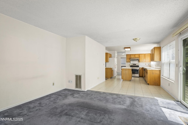 940 Skyway Dr, Reno, NV 89523 - kitchen with stainless steel range with gas cooktop, brown cabinetry, light countertops, light carpet, and open floor plan