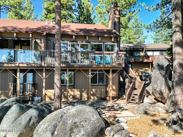 128 Holly Ln Unit B, Stateline, NV 89449 - back of property featuring stairway, a deck, a chimney, and a shingled roof