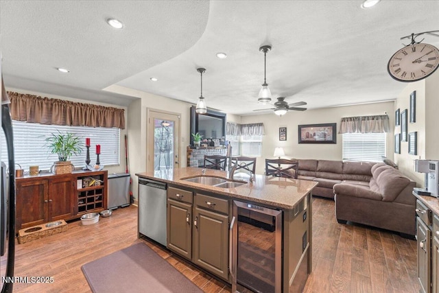 976 Leah Cir, Reno, NV 89511 - kitchen with beverage cooler, dishwasher, open floor plan, a center island with sink, and light stone countertops