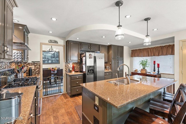 976 Leah Cir, Reno, NV 89511 - kitchen featuring stainless steel appliances, light stone countertops, a kitchen island with sink, a kitchen bar, and light wood-type flooring