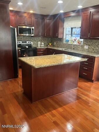 3510 Rancho Cir S, Lake Tahoe, CA 96150 - kitchen featuring stainless steel appliances, tasteful backsplash, wood finished floors, a center island, and light stone countertops