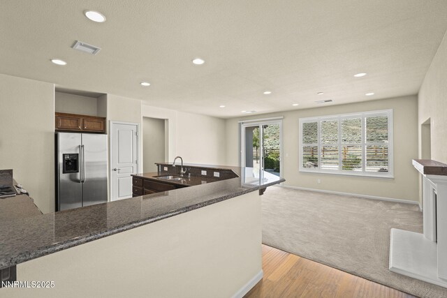 1245 W Del Webb Pkwy, Reno, NV 89523 - kitchen featuring stainless steel refrigerator with ice dispenser, recessed lighting, light colored carpet, light wood-style flooring, and dark stone counters