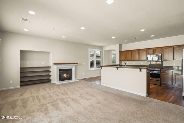 1245 W Del Webb Pkwy, Reno, NV 89523 - kitchen with appliances with stainless steel finishes, dark countertops, recessed lighting, a kitchen breakfast bar, and dark carpet