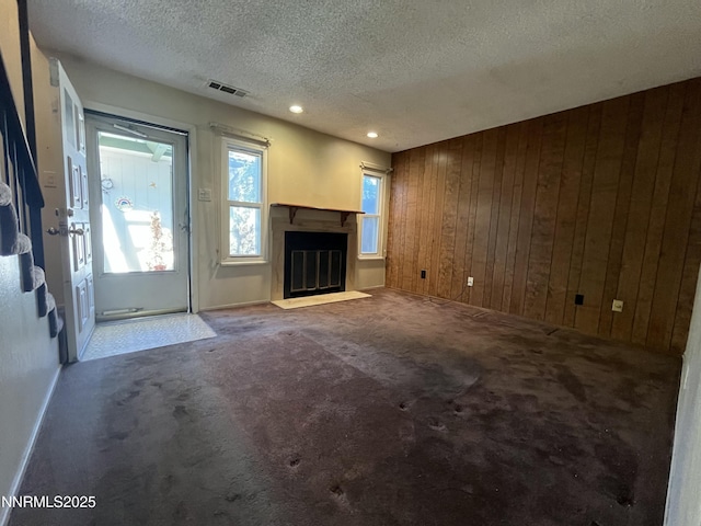 972 Flatcar Ln, Sparks, NV 89431 - unfurnished living room with wooden walls, a textured ceiling, a fireplace with flush hearth, carpet, and recessed lighting