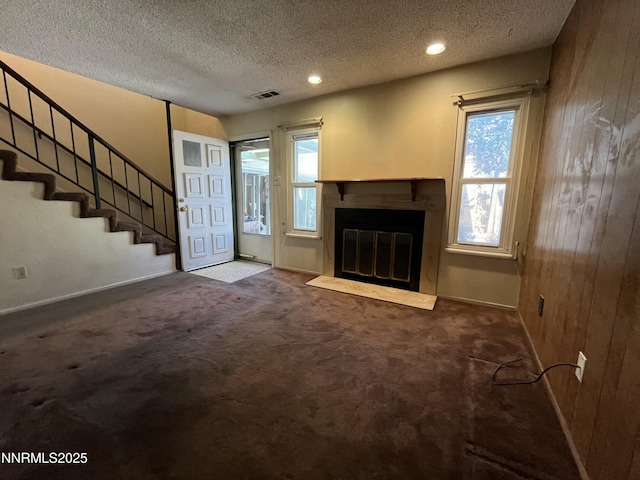 972 Flatcar Ln, Sparks, NV 89431 - unfurnished living room with a textured ceiling, plenty of natural light, carpet flooring, a fireplace with flush hearth, and wood walls