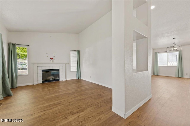 7560 Lighthouse Ln, Reno, NV 89511 - unfurnished living room with plenty of natural light, wood finished floors, a tile fireplace, and a chandelier