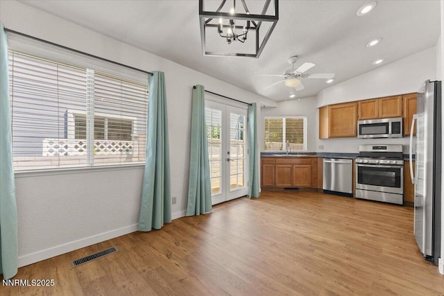 7560 Lighthouse Ln, Reno, NV 89511 - kitchen featuring appliances with stainless steel finishes, brown cabinets, french doors, light wood-style floors, and a chandelier