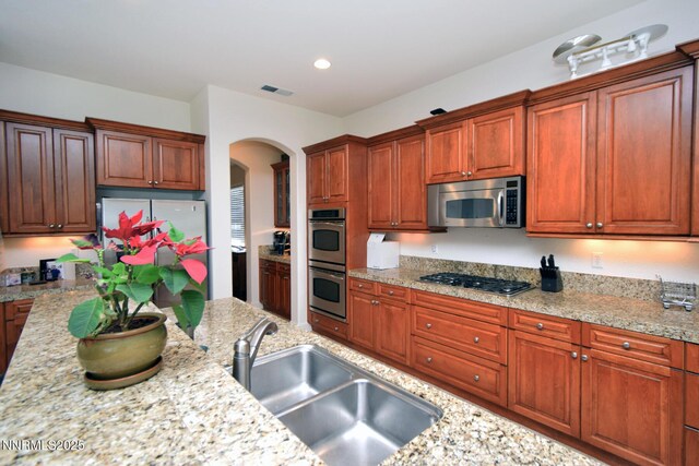 15180 Redmond Lp, Reno, NV 89511 - kitchen with stainless steel appliances, arched walkways, recessed lighting, and light stone countertops