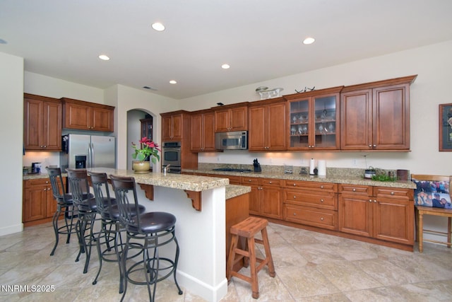 15180 Redmond Lp, Reno, NV 89511 - kitchen with appliances with stainless steel finishes, a kitchen breakfast bar, recessed lighting, arched walkways, and light stone counters