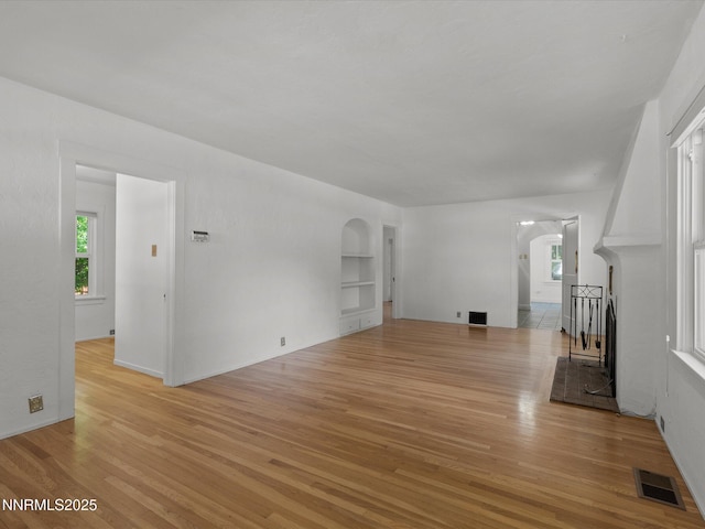 1016 Nixon Ave, Reno, NV 89509 - unfurnished living room featuring arched walkways, light wood-style floors, and built in shelves