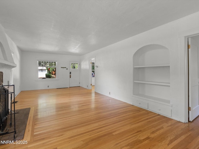 1016 Nixon Ave, Reno, NV 89509 - unfurnished living room featuring light wood-type flooring, built in shelves, and a fireplace with raised hearth
