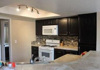 1544 Woodhaven Ln, Sparks, NV 89434 - kitchen with white appliances, tasteful backsplash, light countertops, and dark cabinetry