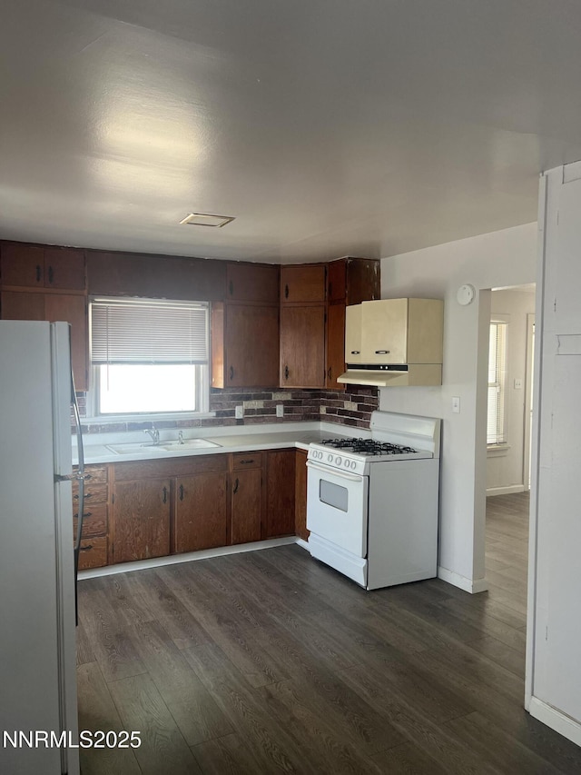 1470 Franklin Ave, Lovelock, NV 89419 - kitchen featuring white appliances, dark wood-type flooring, decorative backsplash, light countertops, and under cabinet range hood