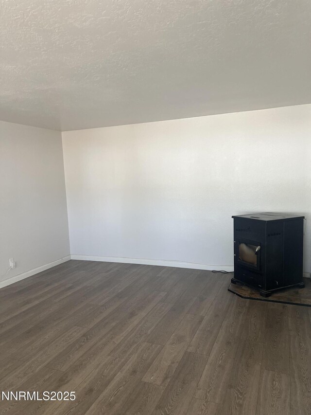 1470 Franklin Ave, Lovelock, NV 89419 - unfurnished living room with a wood stove, dark wood-type flooring, and a textured ceiling