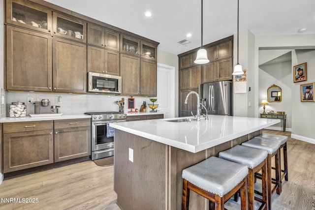 2109 Cast Iron Dr, Reno, NV 89521 - kitchen with stainless steel appliances, backsplash, light wood-type flooring, a breakfast bar area, and recessed lighting