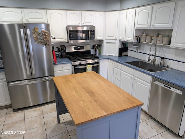 1640 Liston Ave, Reno, NV 89502 - kitchen featuring appliances with stainless steel finishes, wood counters, light tile patterned floors, white cabinetry, and a kitchen island