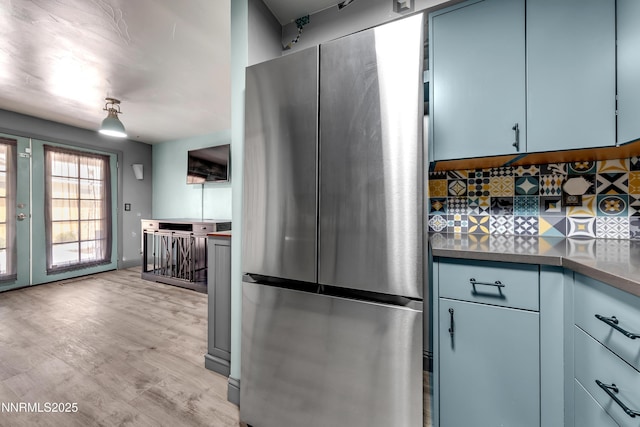 13250 Rolling Sage Pl, Reno, NV 89506 - kitchen featuring freestanding refrigerator, tasteful backsplash, light wood finished floors, and blue cabinetry